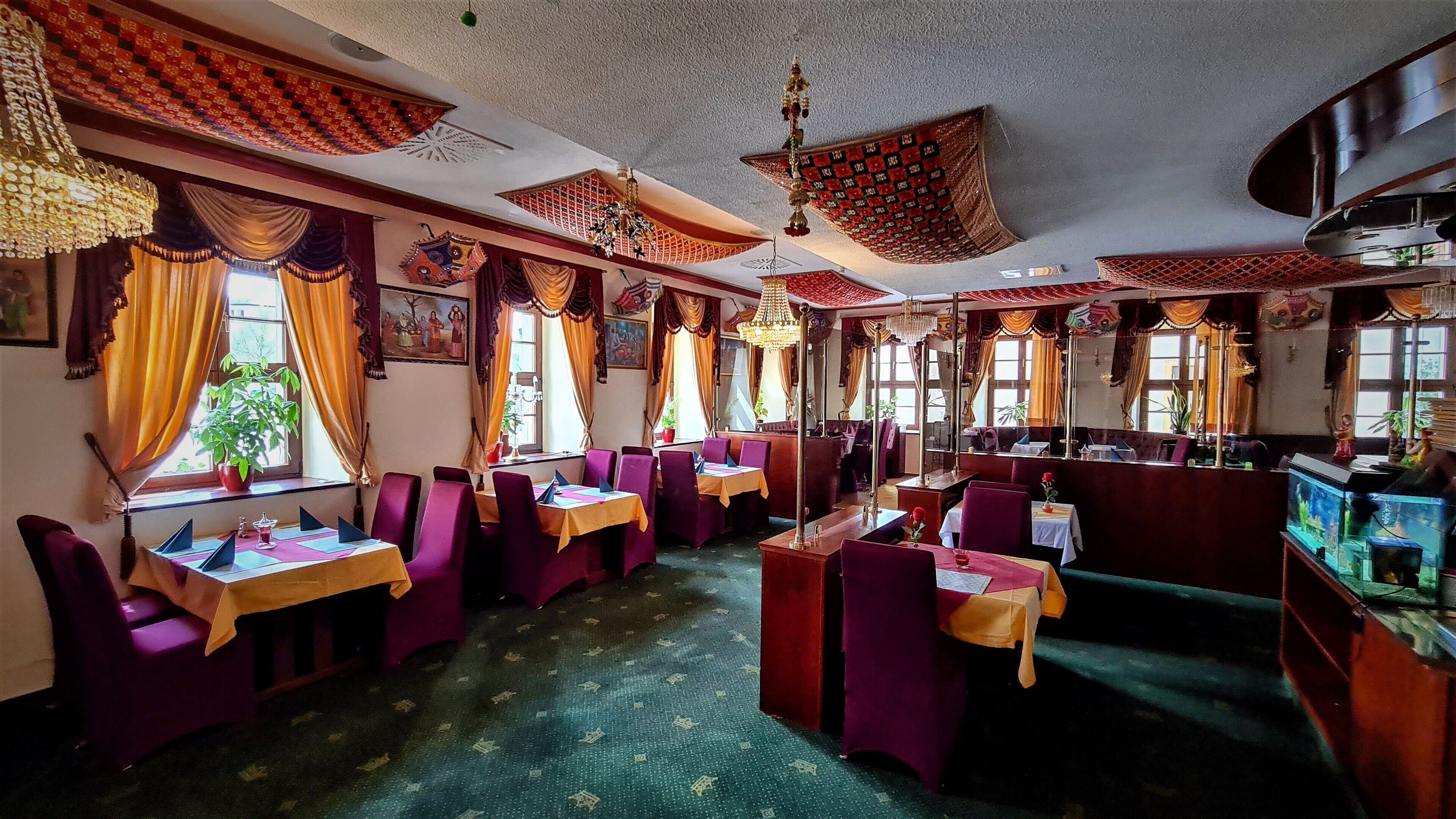 Un restaurant doté de nombreuses tables et de coins salons, avec une décoration traditionnelle et un tapis à motifs.