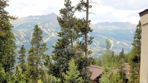 A mountainous landscape with dense forest and a building in the foreground. - Inviting 2BR Townhouse Ideal for Family Getaway (Breckenridge)