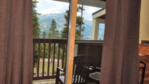 Un balcon avec vue sur les montagnes, une chaise et une table.