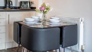 Eine moderne Küche mit Esstisch, Stühlen und einer Blumenvase.