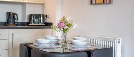 Una cocina moderna con una mesa de comedor, sillas y un jarrón de flores.