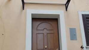 A brown door with a decorative arch, a small step leading up to it, and a metal light fixture above. - Malu's House (Castelluccio Superiore)