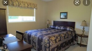 A bedroom with a bed, two bedside tables with lamps, a window with curtains, a desk with a chair, and a picture on the wall. - Super9 inn (Albion)