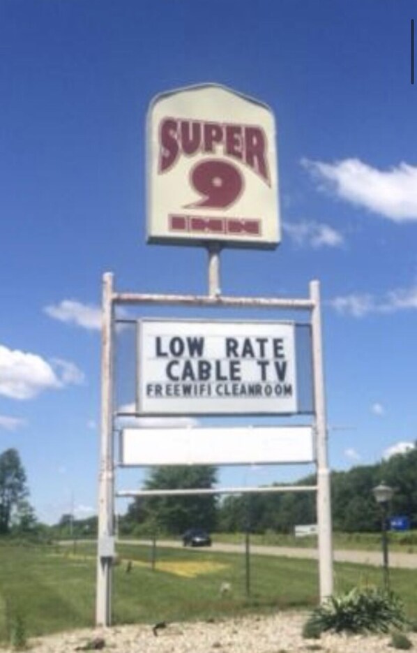 A sign for a Super 9 store advertising low rate cable TV and free wifi in the restroom.