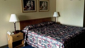 A hotel room with a bed, two wall-mounted lamps, a bedside table with a phone, and two framed floral paintings on the wall. - Super9 inn (Albion)