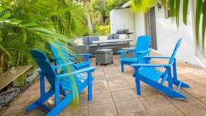Un patio con sillas Adirondack azules, un sofá gris y una mesita.