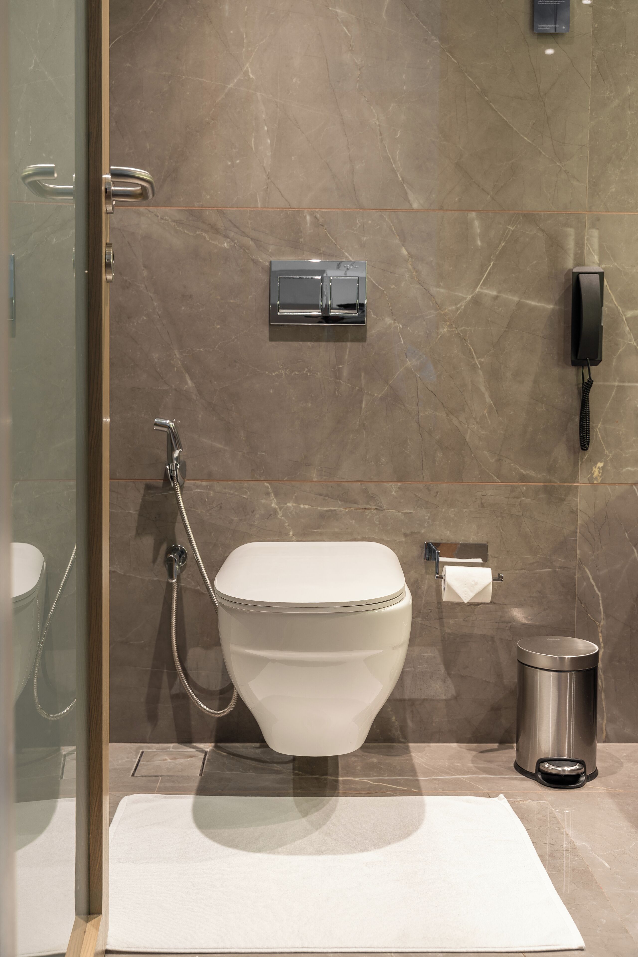 Ein modernes Badezimmer mit Toilette, Dusche, Handtrockner und Mülleimer.