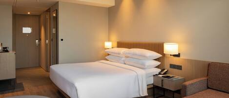 Une chambre d’hôtel comprenant un lit, une table de chevet, une lampe et un coin salon.