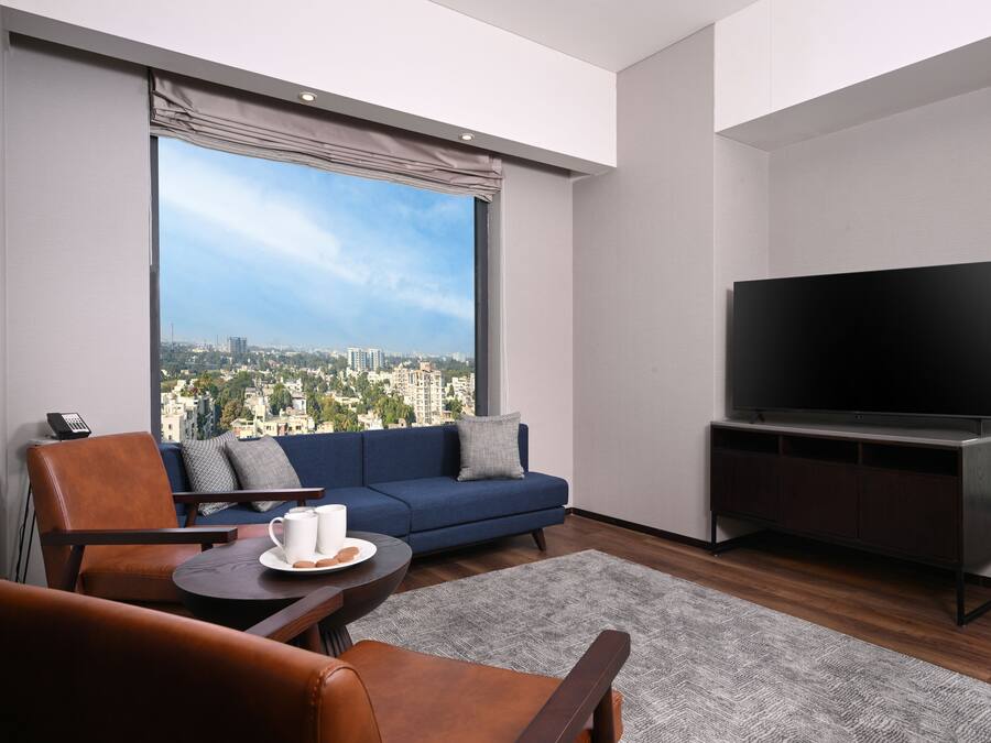 Una sala de estar moderna con un ventanal grande, un sofá, un televisor y una mesita de centro.