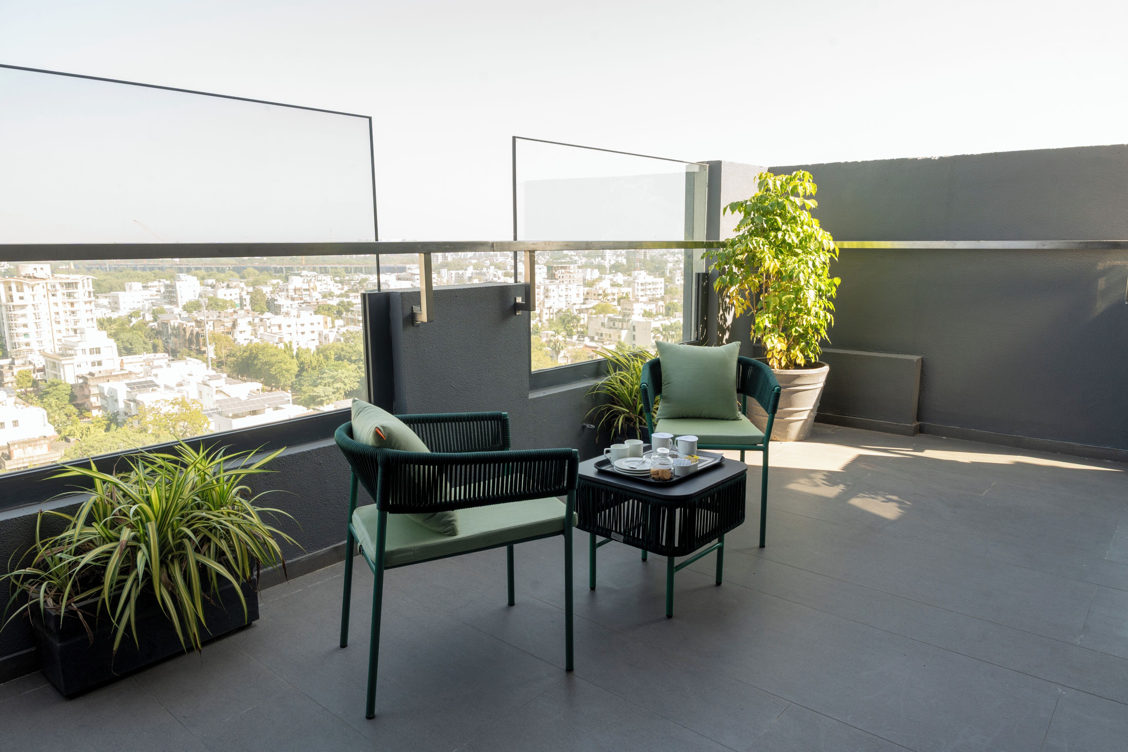 Un balcón con dos sillas, una mesa y plantas en macetas.
