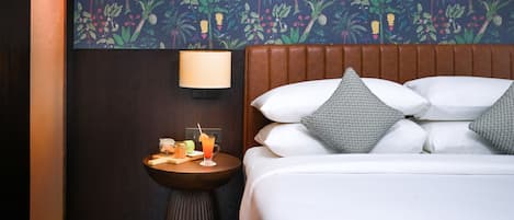Habitación de hotel con cama, mesita de noche, lámpara y pared decorada con un estampado floral tropical.