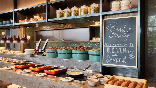 Montaje de desayuno tipo buffet con diversos alimentos y recipientes.