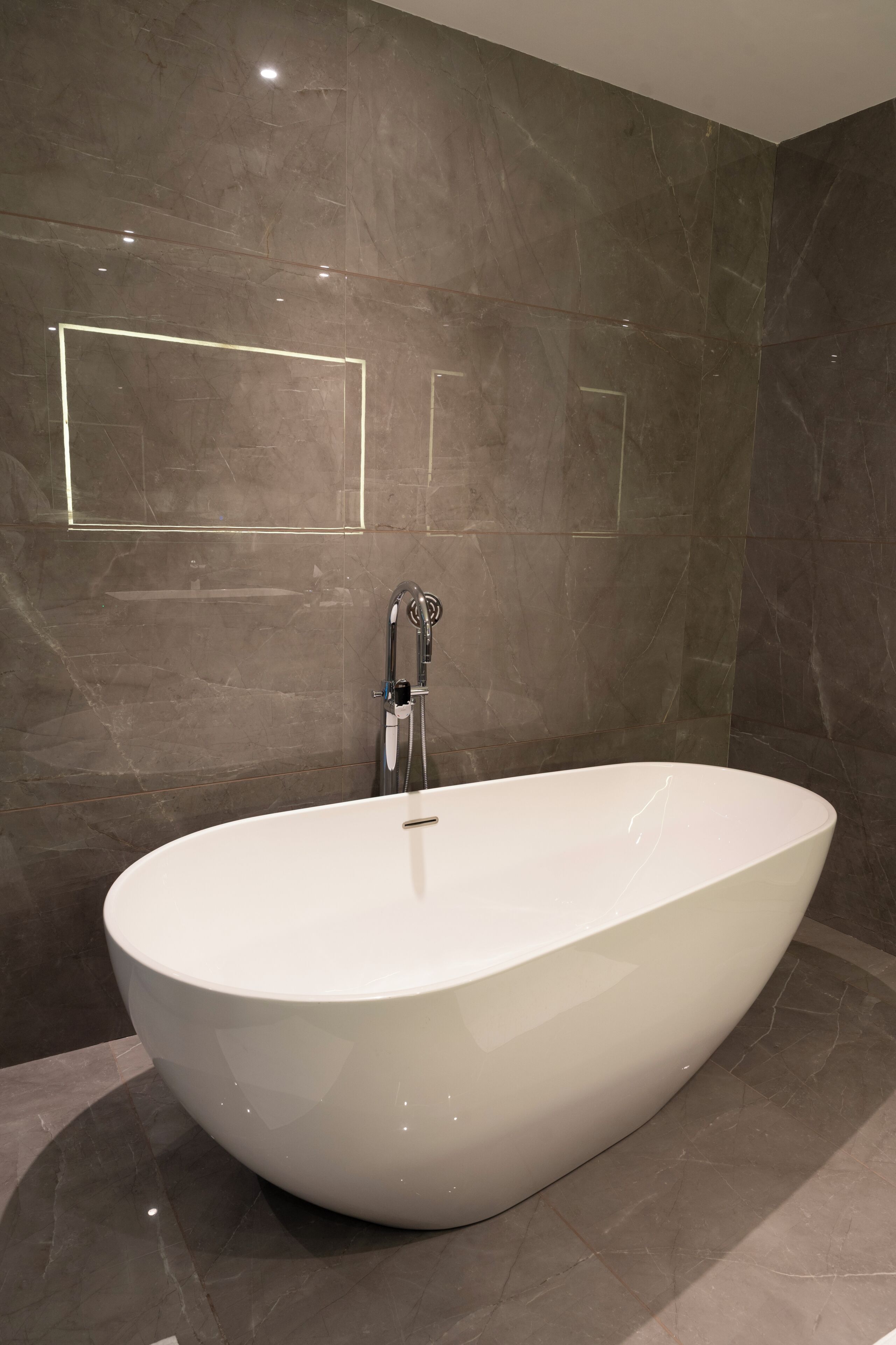 Un baño moderno con una bañera independiente, paredes de mármol y un diseño minimalista.