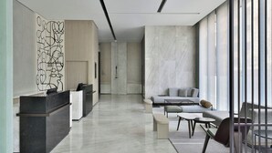 Un lobby moderno de hotel con mostrador de recepción, zona de estar y grandes ventanales.