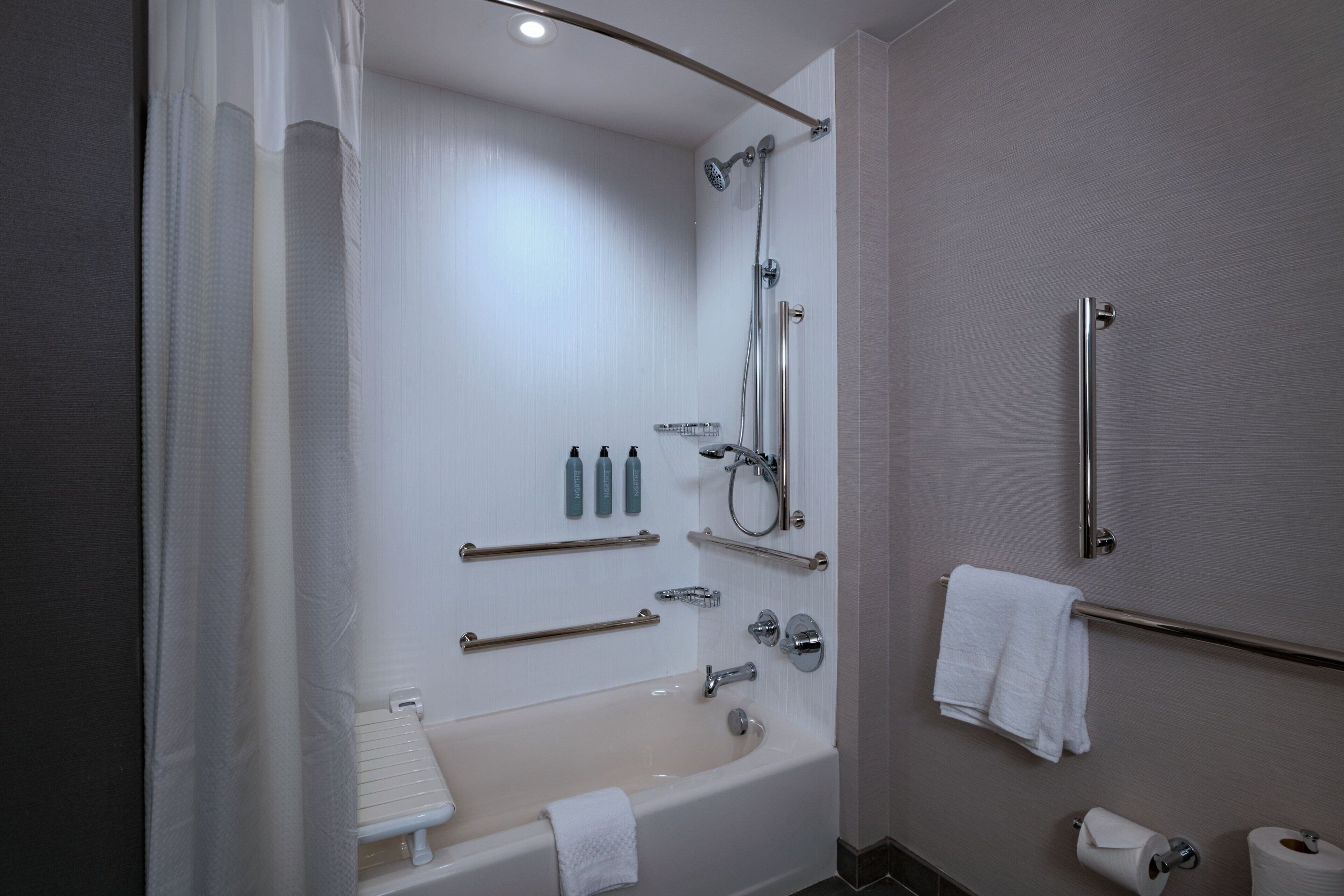 Un baño moderno con bañera, ducha y barras de apoyo.