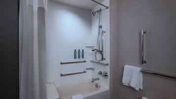 Un baño moderno con bañera, ducha y barras de apoyo.