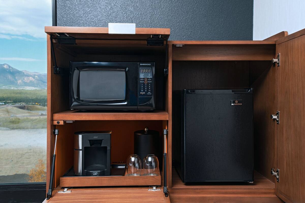 Una kitchenette compacta con microondas, cafetera y refrigerador.