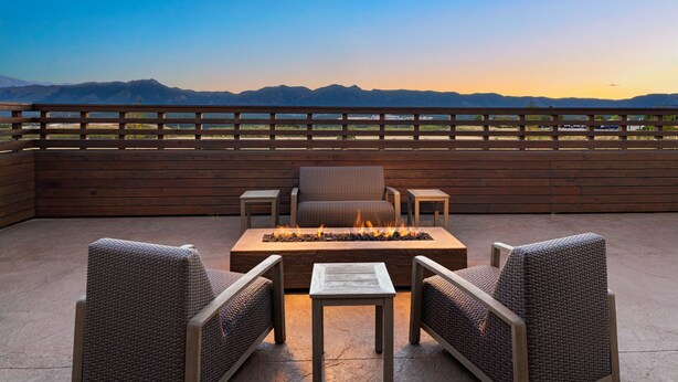 Un patio exterior con una chimenea, mobiliario de mimbre y vistas a las montañas.
