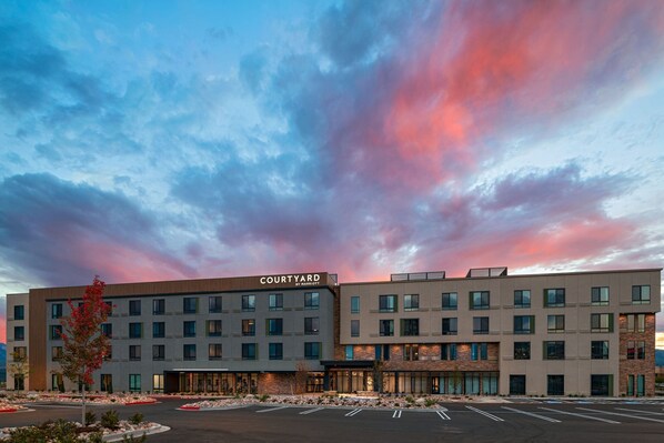 Un hotel Courtyard by Marriott con diseño moderno, varios pisos y un estacionamiento.