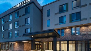 Un hotel moderno con entrada cubierta, varios pisos y un llamativo letrero de "Courtyard by Marriott".