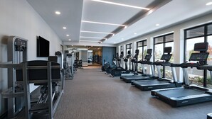 Un gimnasio moderno con cintas de correr, máquinas de pesas y un dispensador de agua.