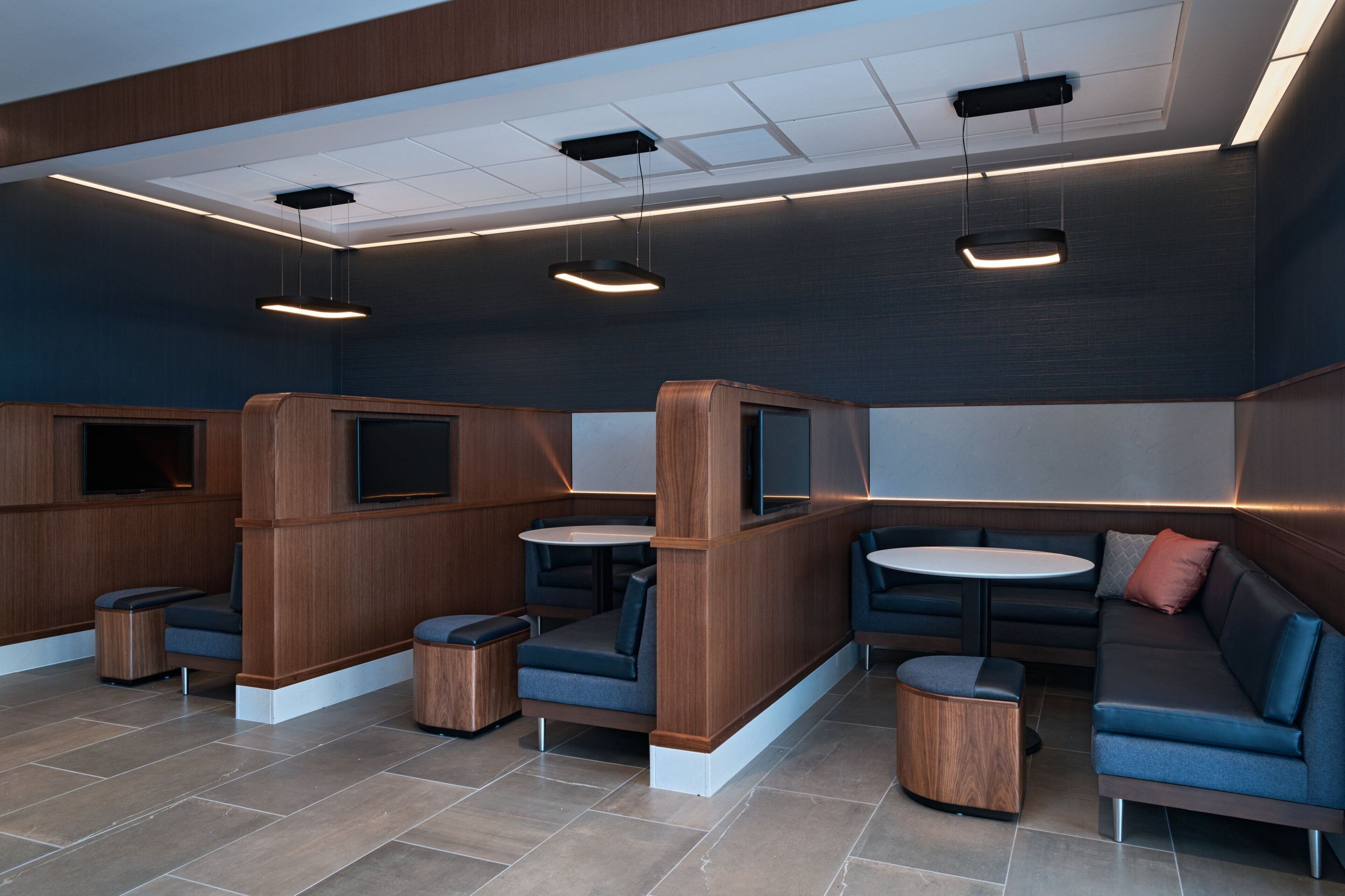 Un área de lounge moderna con arreglos de asientos, incluyendo sofás y mesas, e iluminación empotrada en el techo.