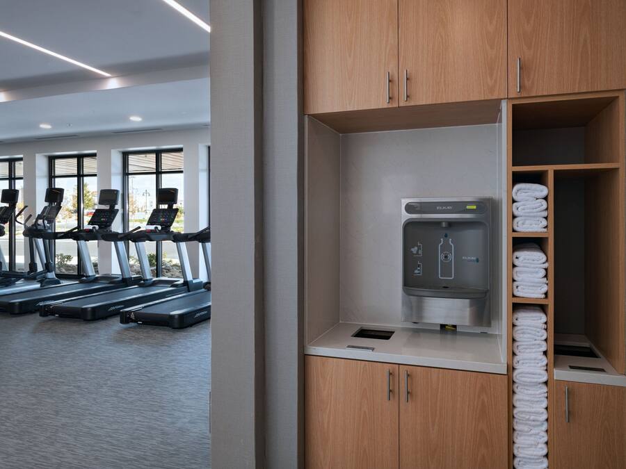 A gym with treadmills, a water dispenser, and neatly stacked towels.