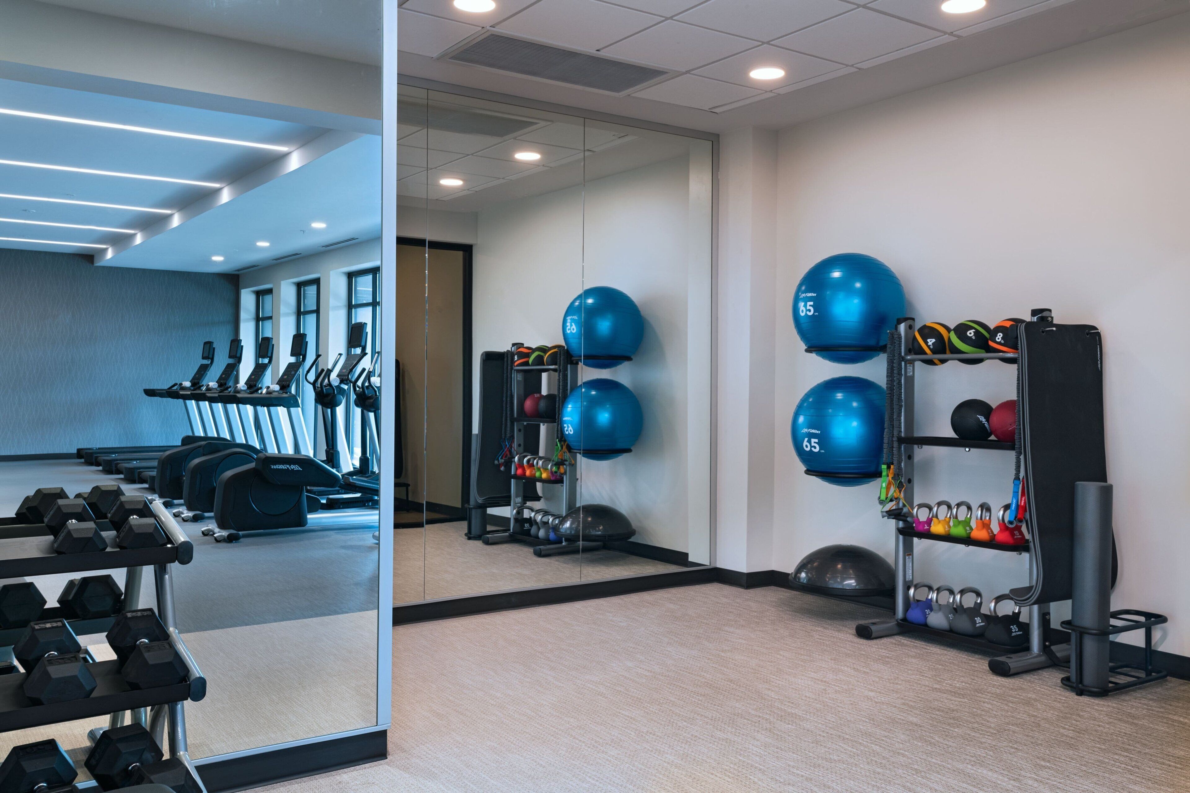 A gym with exercise equipment, including treadmills, dumbbells, and kettlebells.
