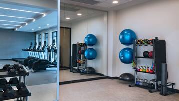 A gym with exercise equipment, including treadmills, dumbbells, and kettlebells.