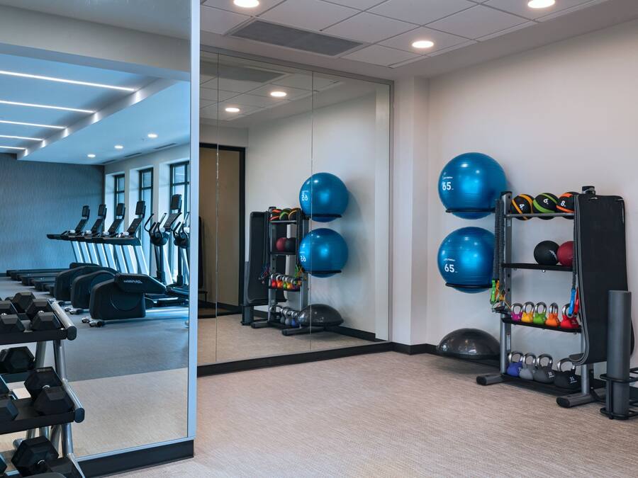 A gym with exercise equipment, including treadmills, dumbbells, and kettlebells.