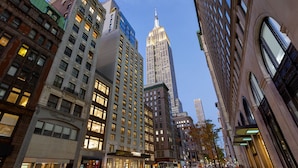 A city street with tall buildings, including a prominent skyscraper with a spire. - Le Meridien New York, Fifth Avenue (New York)