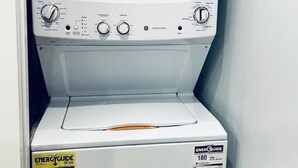 A front view of a white washing machine with control knobs and a yellow EnergyGuide sticker. - Luxe City Hall Suite by Rittenhouse Square (Philadelphia)