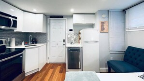 A compact kitchen with white cabinets, a microwave, a dishwasher, and a refrigerator. - Luxe City Hall Suite by Rittenhouse Square (Philadelphia)