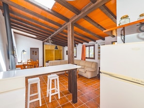A compact kitchen with a white countertop, two stools, a wooden ceiling, and a tiled floor. - Cubo's Casita Rural Haro / free wifi / private pool (Cártama)