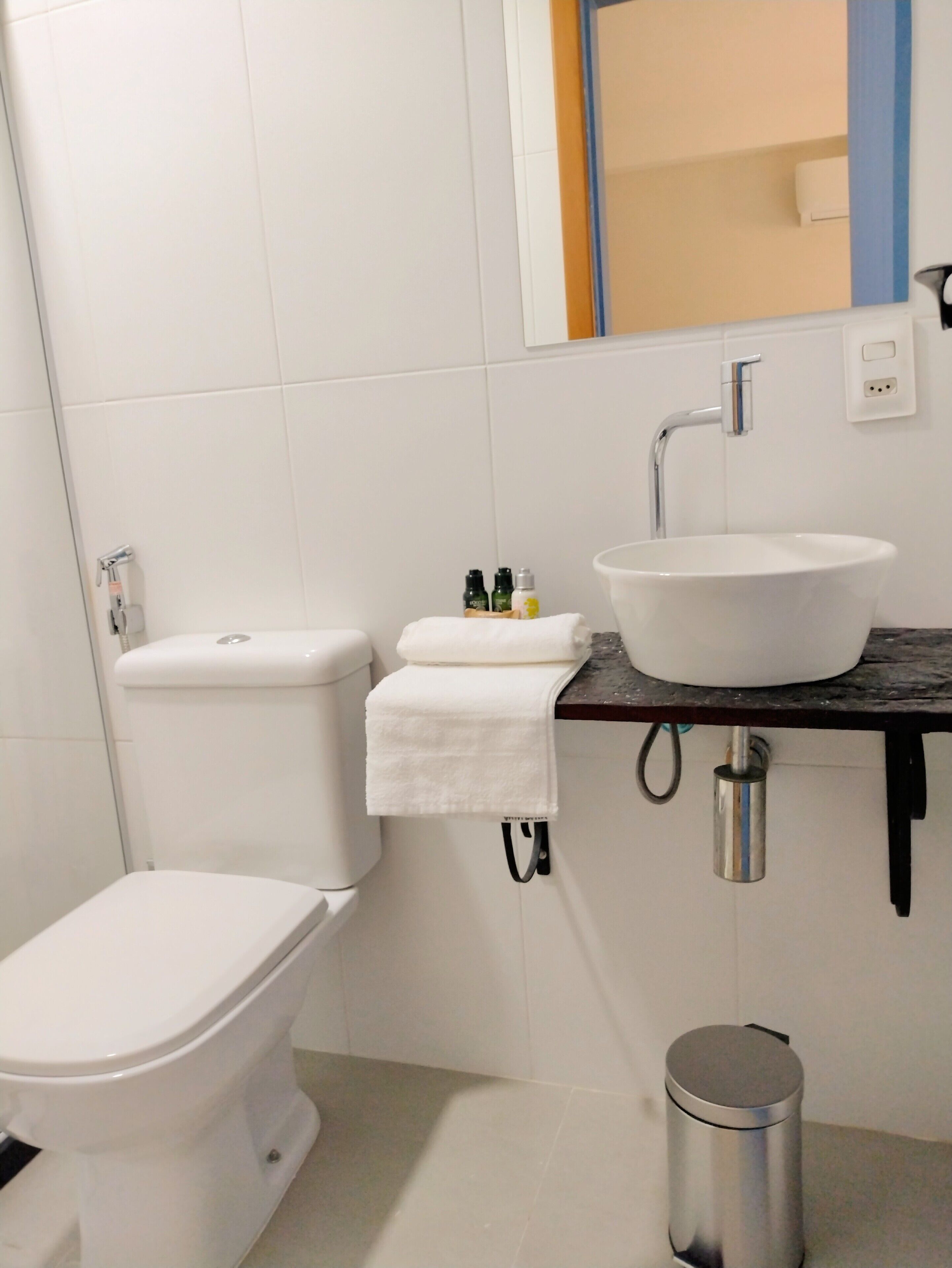 Un baño moderno con inodoro, lavamanos y cubo de basura.