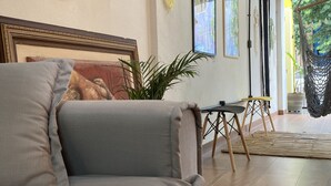 Una sala de estar acogedora con un sofá, obras de arte enmarcadas y una hamaca.