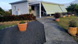 Una casa moderna con un porche cubierto, plantas en macetas y un camino de grava.