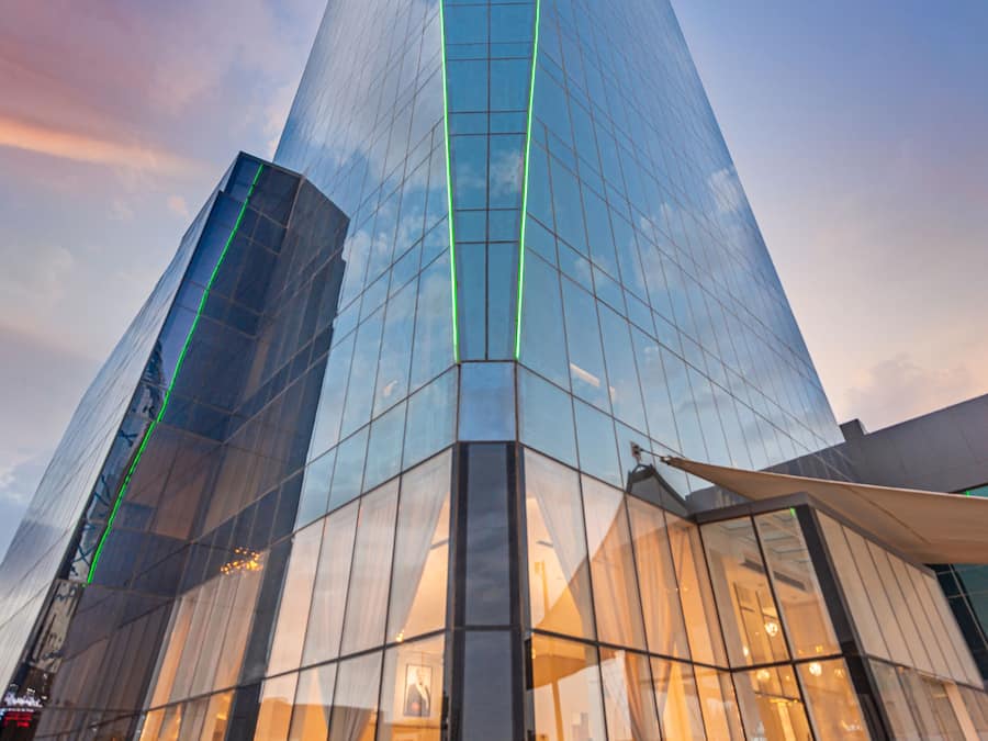 A modern glass building with a reflective facade and a green vertical line.