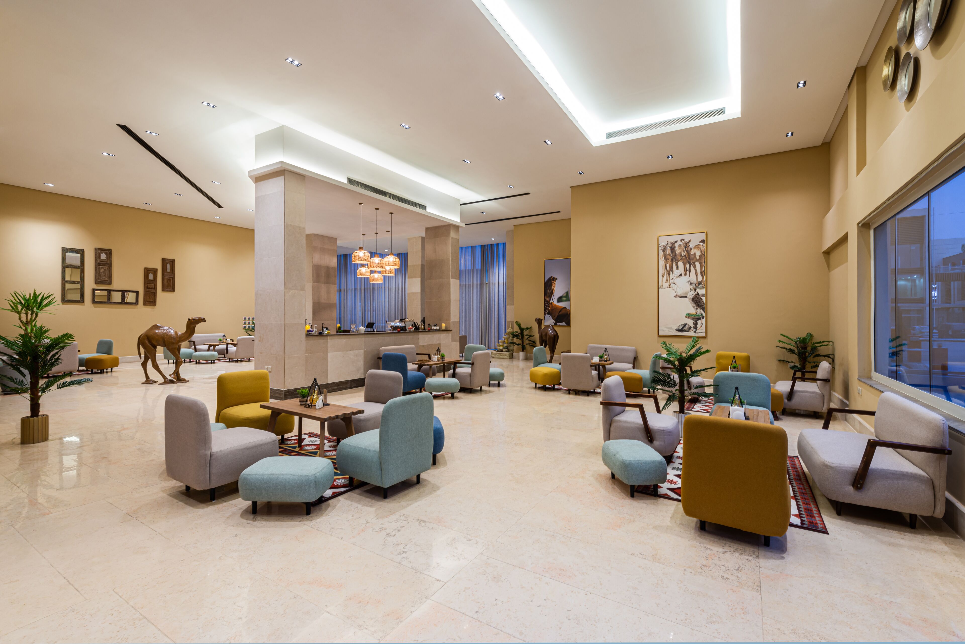 A spacious lobby with multiple seating areas, a reception desk, and a large window providing a view of the outside.