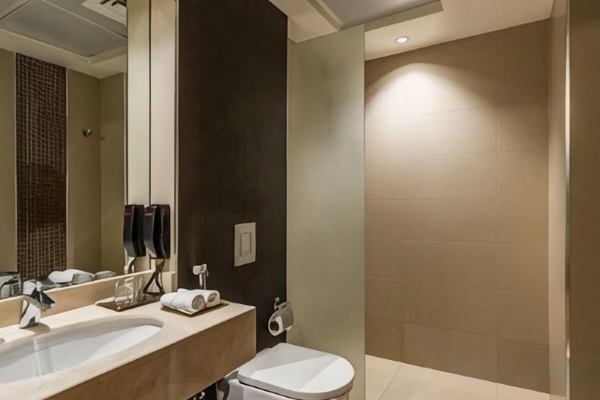 A modern bathroom with a double sink, toilet, and a large mirror.
