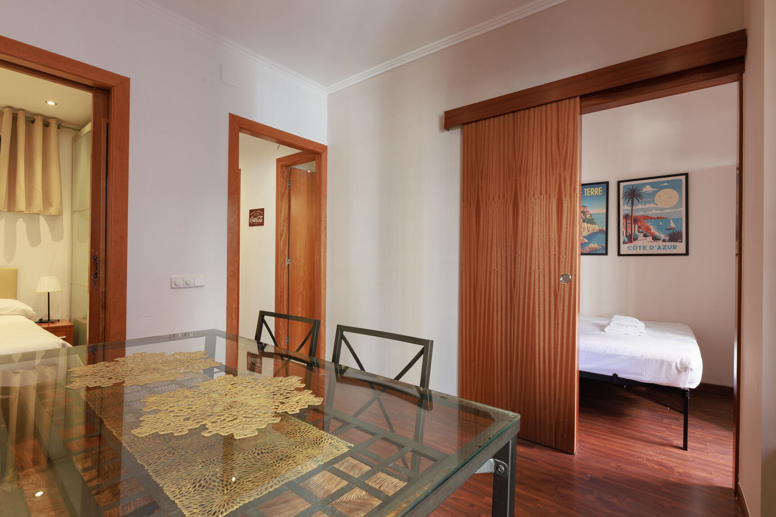 Une chambre d’hôtel avec une table à manger en verre, un lit et un placard à portes coulissantes.