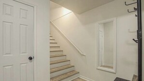 Uma escadaria leva a um patamar com um porta-roupas e um banco.