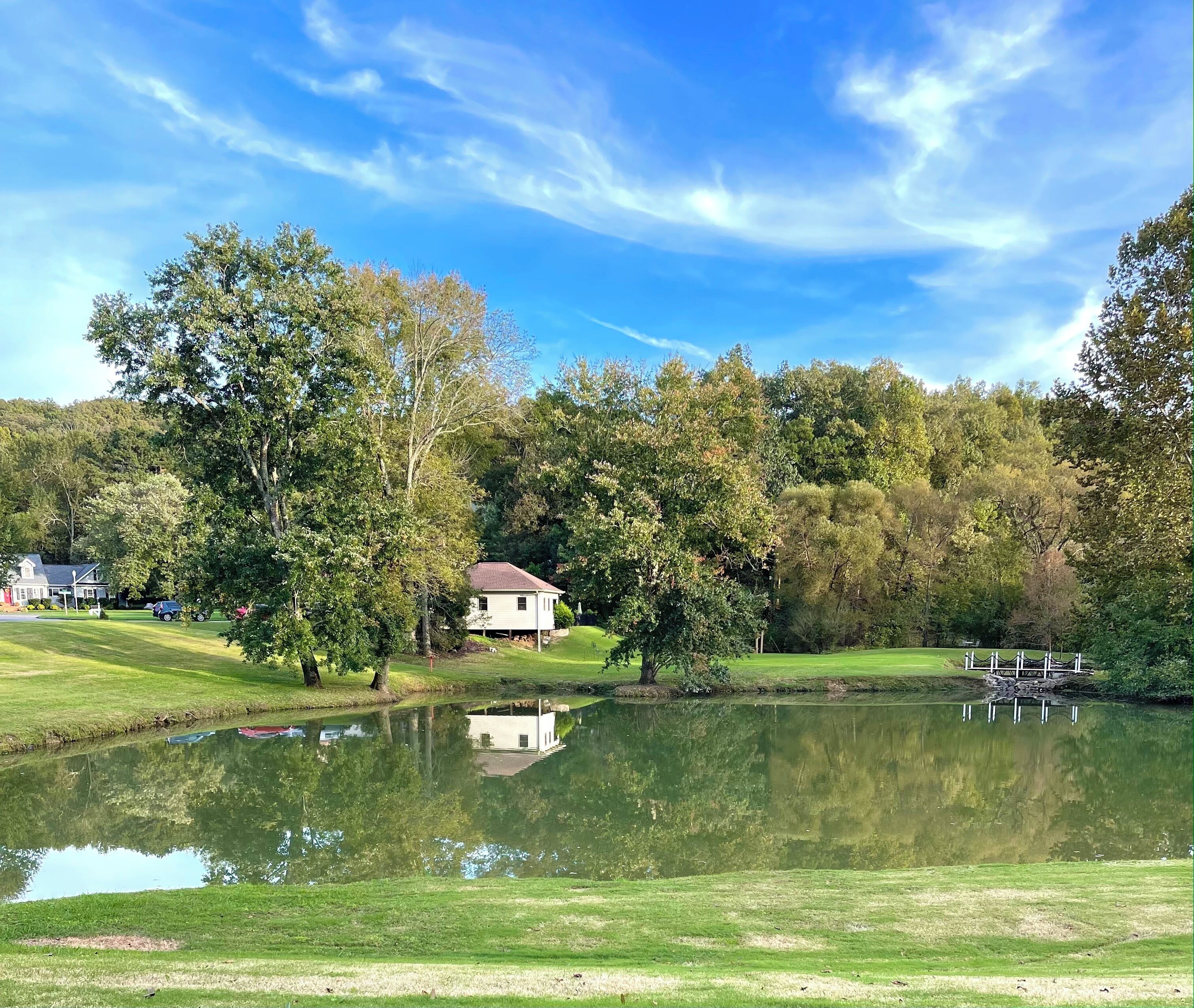Une scène paisible au bord d’un lac, avec une maison, des arbres et un quai.