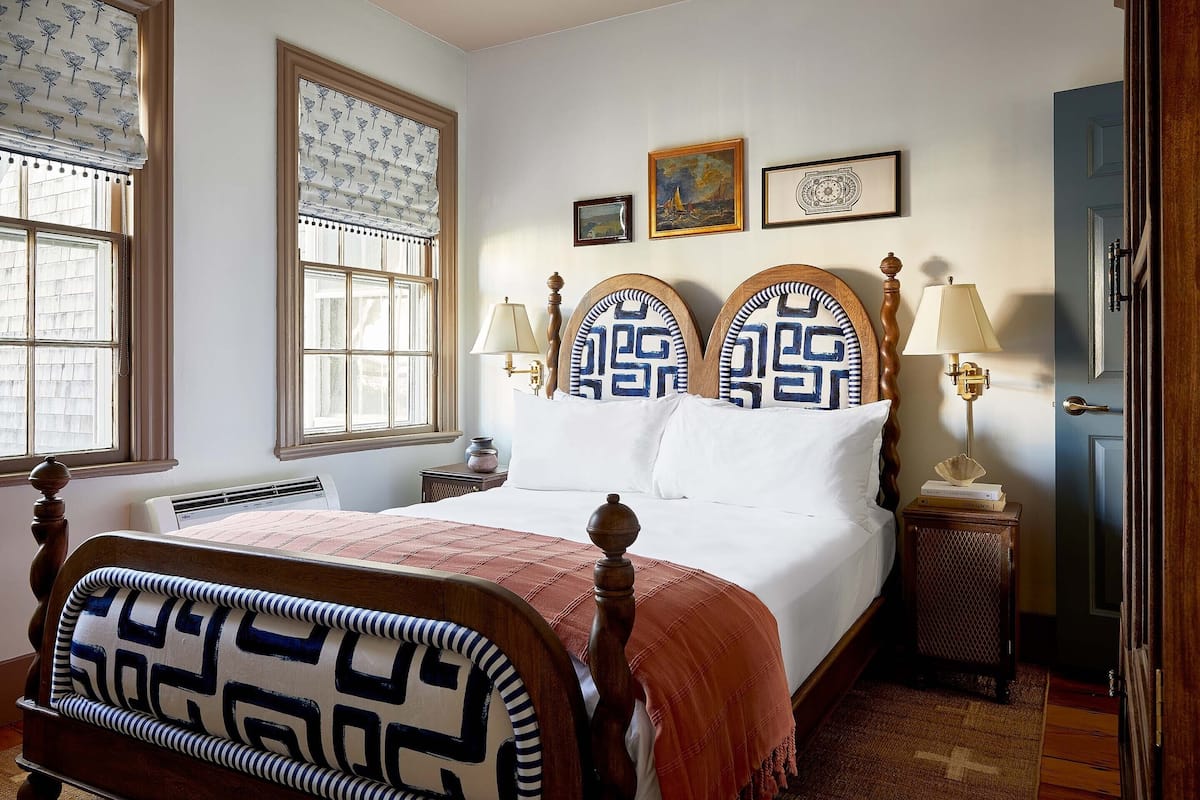 A bedroom with a large bed, two bedside tables, a nightstand, and a door.