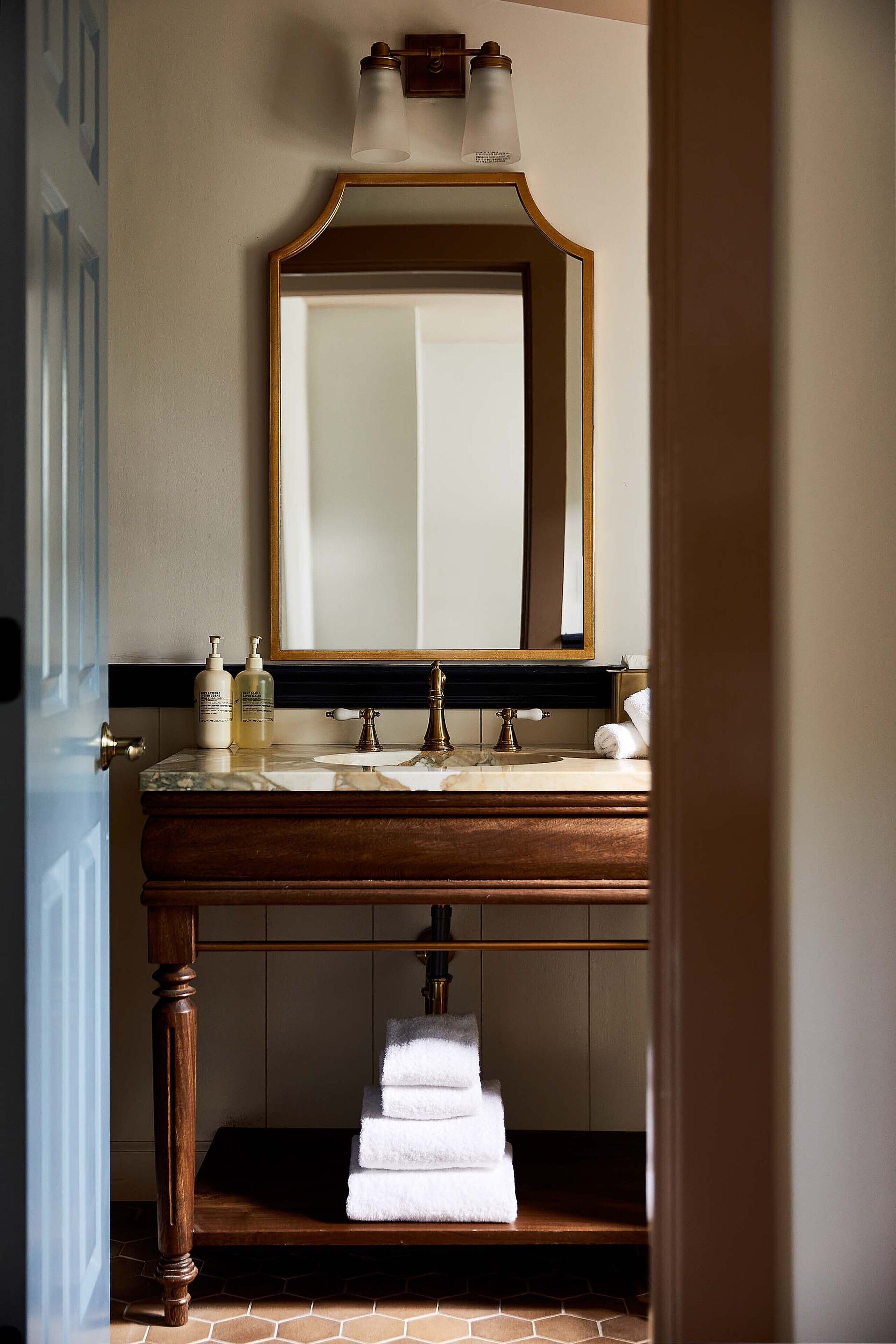 Un baño con tocador de madera, un espejo grande y un perchero para toallas.