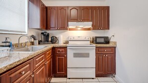 Una cocina con armarios de madera, una estufa blanca, un microondas y una encimera de granito.