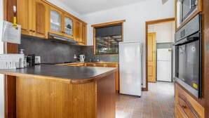 Une cuisine avec des meubles en bois, un îlot central, un réfrigérateur et une cuisinière.