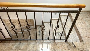 Una barandilla de madera con un pasamanos de metal en una escalera.