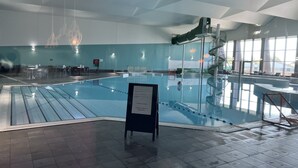 Ein Hallenbad mit Rutsche, Sitzgelegenheiten und einem Hinweisschild.