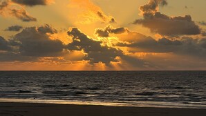 Ein Strand mit Wellen und einem Sonnenuntergang.